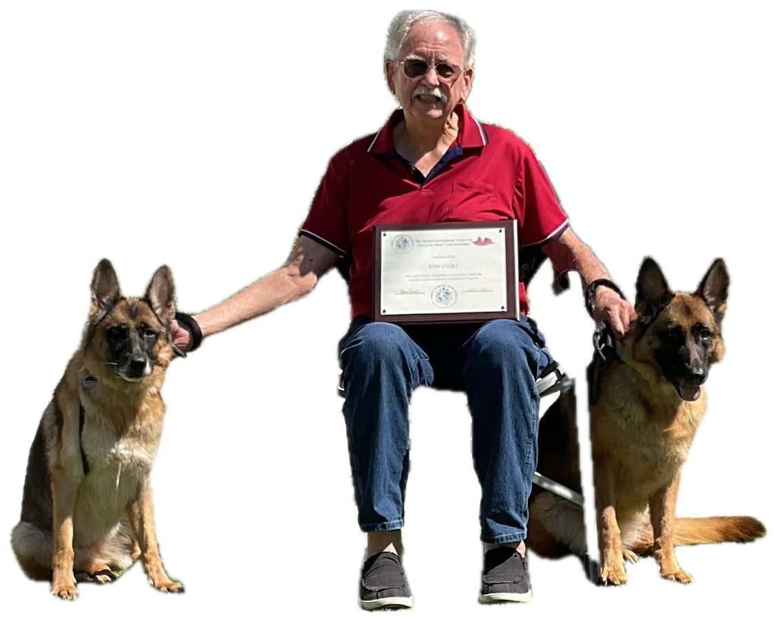 Ron Cable holding his animal communication certificate, a German Shepherd on each side